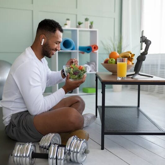 full-shot-man-eating-eating-salad (1) man eating salad with workout equipment